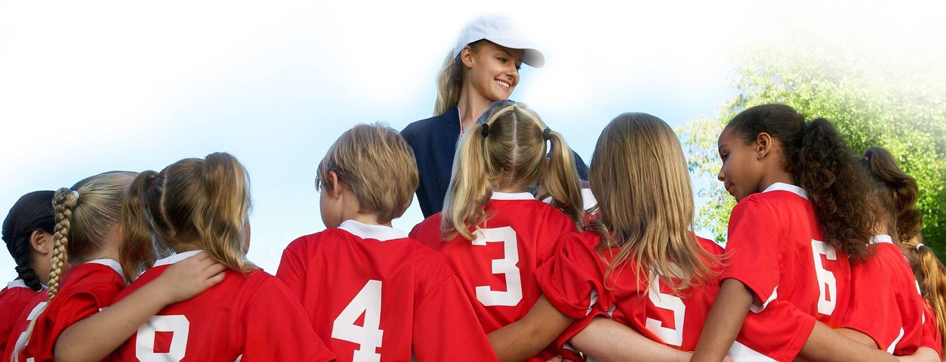 A group of young girls in red jerseys and hats.